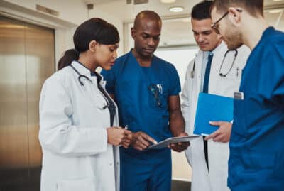 multiracialteamofdoctorsdiscussingapatientstandinggroupedin