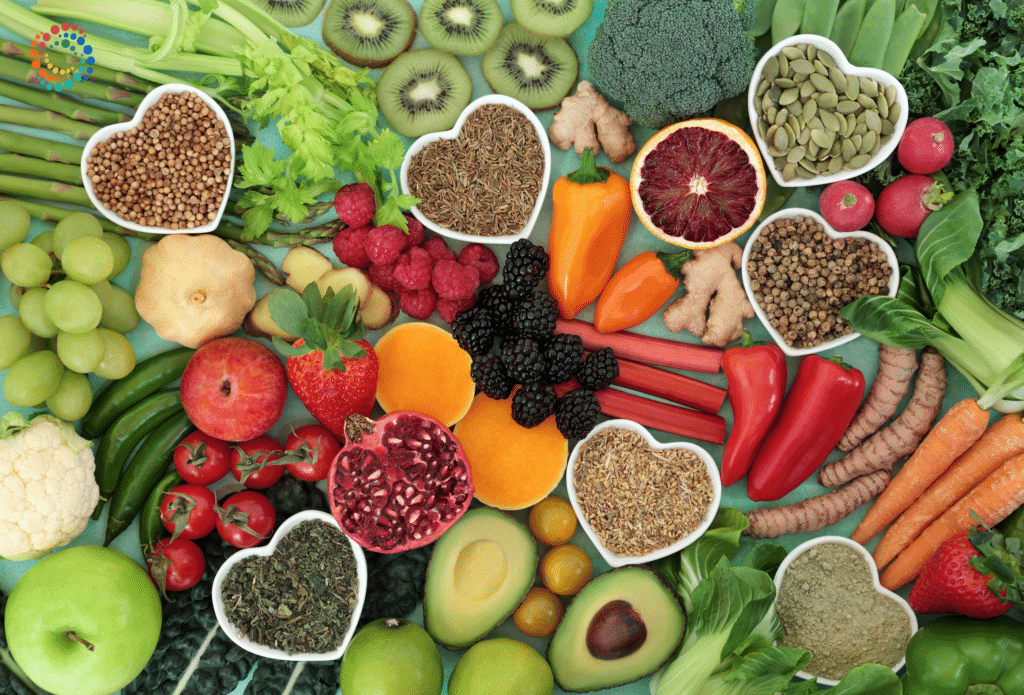 A wide array of colorful fruits and vegetables with heart shaped bowls scattered amongst the image with nuts, seeds and spices in them.